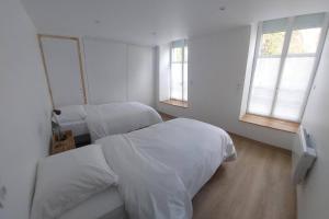 a white room with two beds and two windows at Le Héron in Thury-Harcourt