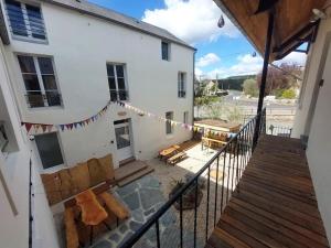 einen Balkon in einem weißen Gebäude mit einer Terrasse in der Unterkunft Le Héron in Thury-Harcourt