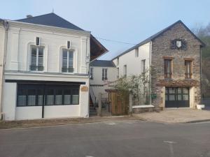 ein weißes Haus mit einer Garage und einem Backsteingebäude in der Unterkunft Le Héron in Thury-Harcourt
