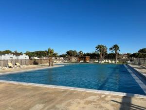 a large swimming pool with blue water in a yard at Mobil Home de Marine in Port-la-Nouvelle