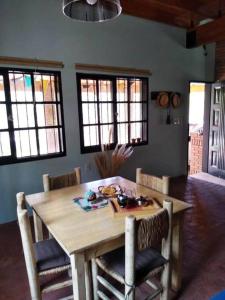 CASA EN MANANTIALES (Potrerillos, Mendoza) في بوتريريلوس: طاولة وكراسي خشبية في غرفة بها نوافذ