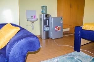 a living room with a blue couch and a refrigerator at Trendy Homes Studio BnB in Bungoma