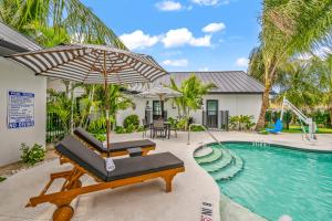 a pool with an umbrella and a chair next to a house at The Retreat at Anna Maria Island Inn in Bradenton Beach