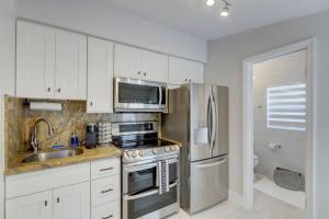 a kitchen with white cabinets and a stainless steel refrigerator at Laguna @ Casa Del Sol in Fort Lauderdale