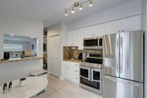 a kitchen with white cabinets and a stainless steel refrigerator at Laguna @ Casa Del Sol in Fort Lauderdale