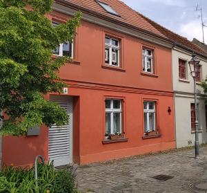 a red house with white windows on a street at Omas Linde in Brandenburg an der Havel