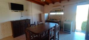 a kitchen with a large wooden table and a television at Cabañas La Gringa in Potrero de los Funes