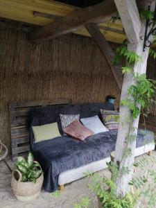 a bed with pillows on it sitting under a thatch roof at La romance de Laura in Arrest