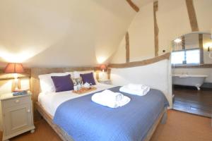a bedroom with two beds and a bath tub at The Cross Wing, High Ash Farm in Peasenhall