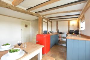 eine Küche mit einem roten Kühlschrank und einem Tisch in der Unterkunft The Cross Wing, High Ash Farm in Peasenhall