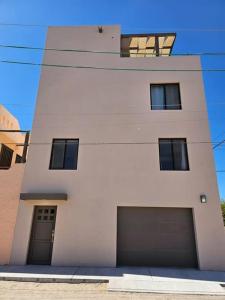 ein weißes Gebäude mit zwei Garagen und zwei Fenstern in der Unterkunft Pueblo Townhouse By Monte vista in Puerto Peñasco