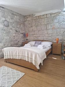 1 dormitorio con 1 cama con pared de piedra en Apartment Tonka en Trogir