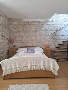 1 dormitorio con cama y pared de piedra en Apartment Tonka en Trogir