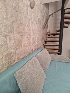 Habitación con paredes de piedra, cama y escalera. en Apartment Tonka en Trogir