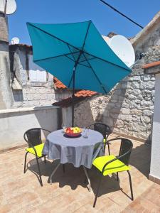 una mesa con una sombrilla azul en el patio en Apartment Tonka en Trogir