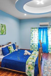 a bedroom with a bed and blue walls at Villa De Cruz - Presidential Suite in Scarborough
