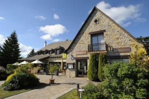 a large brick building with a patio in front of it at Le Relais De La Poste in Neuvéglise