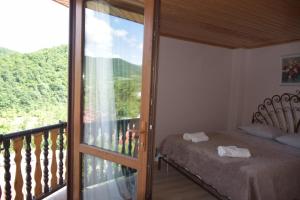 1 dormitorio con balcón con cama y puerta de cristal en Guest House Ilto en Akhmety