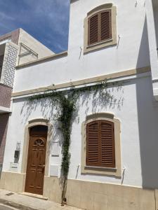 a white building with brown doors and windows at Casa Pombalinho, an old Fisherman Cottage in Fuzeta