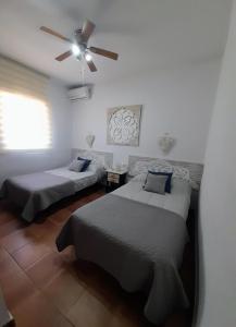 una camera con 2 letti e un ventilatore a soffitto di Villa Lola 14 a Chiclana de la Frontera