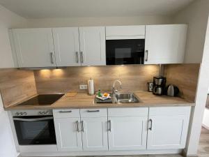 a kitchen with white cabinets and a sink at Ferienwohnung Wegner in Trassenheide