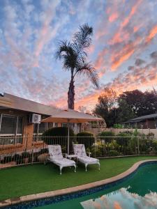 a patio with two chairs and a table and a palm tree at Villa Rose Cottages in Bloemfontein