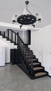 a black staircase in a house with a chandelier at Casa Florus in Sighetu Marmaţiei