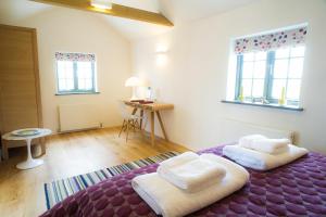 a bedroom with a purple bed with two white towels at The Seed Store, High Ash Farm in Peasenhall