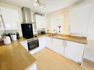 uma cozinha com armários brancos e piso em madeira em Flat 3 - Seabreeze - 2 bedrooms em Southbourne