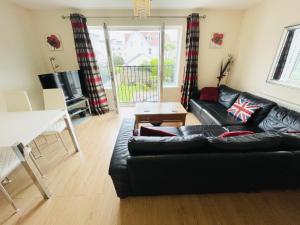 uma sala de estar com um sofá de couro preto e uma mesa em Flat 3 - Seabreeze - 2 bedrooms em Southbourne