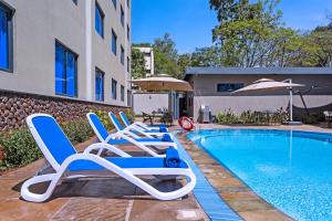 a row of lounge chairs next to a swimming pool at Saggys Suites Hotel & Spa in Nairobi