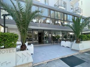 een gebouw met twee palmbomen ervoor bij Hotel Eiffel in Rimini