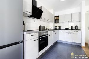 eine Küche mit weißen Schränken und einem schwarzen Geschirrspüler in der Unterkunft Pineapple Apartments Dresden Zwinger VII - 78 qm - 1x free parking - in Dresden