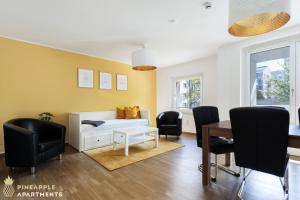 ein Wohnzimmer mit einem Tisch und schwarzen Stühlen in der Unterkunft Pineapple Apartments Dresden Zwinger VII - 78 qm - 1x free parking - in Dresden