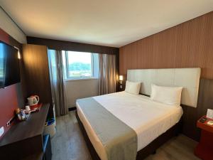 um quarto de hotel com uma cama e uma televisão em eSuites Hotel Recreio Shopping no Rio de Janeiro