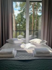 sypialnia z łóżkiem z poduszkami i oknem w obiekcie REMAR - Apartamentai prie Necko Ežero w mieście Augustów