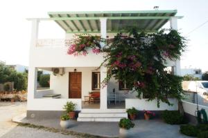 ein weißes Haus mit einem Baum mit rosa Blüten in der Unterkunft Kostia Studios in Skyros