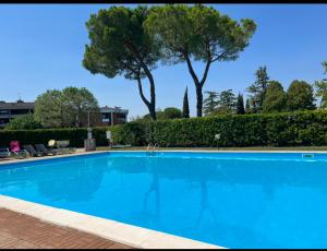une grande piscine bleue avec des arbres en arrière-plan dans l'établissement fior di loto, à Desenzano del Garda