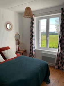 Un dormitorio con una cama azul y una ventana. en Havre de paix à Carteret !, en Barneville-Carteret