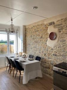 comedor con mesa con sillas y pared de piedra en Havre de paix à Carteret !, en Barneville-Carteret