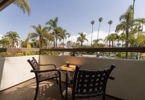 uma mesa e duas cadeiras numa varanda com palmeiras em The Franciscan Hotel em Santa Bárbara