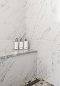 a white bathroom with three soap bottles on a shelf at The Franciscan Hotel in Santa Barbara
