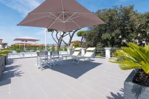 a patio with a table and chairs and an umbrella at Lido Luxury Villas in Lido di Camaiore