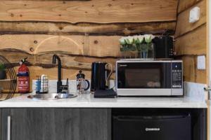 a kitchen counter with a microwave and a sink at Greenview Glamping Pods in Bannvale