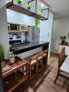 a kitchen with a black counter and wooden chairs at Apartamento Quartos Vista Praia do Morro Casais Melhor Localização, Super Completo 4 TVs Led, Camas-box Novas, 2 Quartos Suíte, Garagem, 2 Ar Condicionados, Wifi 300mb, Varanda Gourmet, Cervejeira, Novo para Famílias in Guarapari