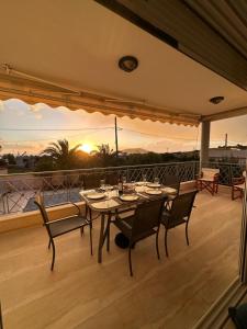 a table and chairs on a balcony with the sunset at Villa thymari in Sounio