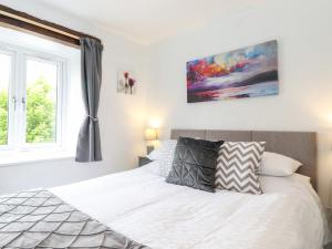 a bedroom with a white bed and a window at Corner Cottage in Carnforth