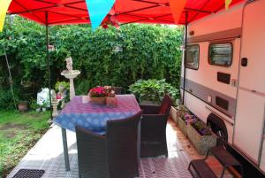a table and chairs with a red umbrella and a van at B&B Öland Caravan "Juf Jansen" in Ottoland +1 photo