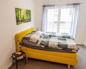 a yellow bed in a room with a window at Ferienwohnung am Erzberg in Fürth