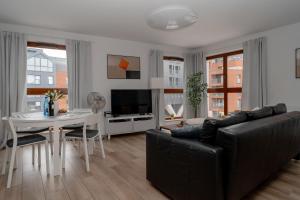 a living room with a black couch and a table at TOTU HOME Waterlane Island Apartments in Gdańsk
